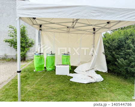 Temporary event infrastructure with canopy shelter and utility containers on lawn Temporary event infrastructure with canopy shelter and utility containers on lawn 140544786