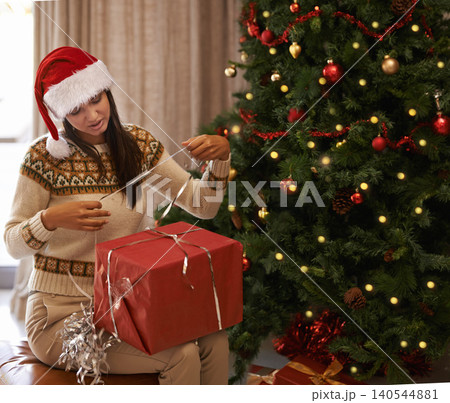 Woman, Christmas and wrapping a box by a tree for festive season, holiday or special surprise at home. Decoration, female person busy with ribbon for gift, package or present for winter celebration Woman, Christmas and wrapping a box by a tree for festive season, holiday or special surprise at home. Decoration, female person busy with ribbon for gift, package or present for winter celebration 140544881