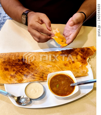 Man Eating South Indian Dosa in a Restaurant 140544889