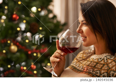Christmas, smile and wine with woman in living room of home, drinking alcohol to relax for celebration. Face, thinking and festive with happy young person in apartment for December holiday event Christmas, smile and wine with woman in living room of home, drinking alcohol to relax for celebration. Face, thinking and festive with happy young person in apartment for December holiday event 140545036