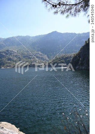 Serene alpine lake surrounded by layered mountain ridges and pine branches. Serene alpine lake surrounded by layered mountain ridges and pine branches. 140545040