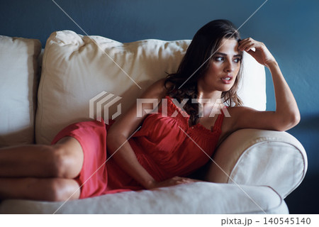 Relax, thinking and style with woman on sofa in studio on blue background for feminine wellness. Calm, fashion and vision with confident or serious young person in red dress for valentines day Relax, thinking and style with woman on sofa in studio on blue background for feminine wellness. Calm, fashion and vision with confident or serious young person in red dress for valentines day 140545140