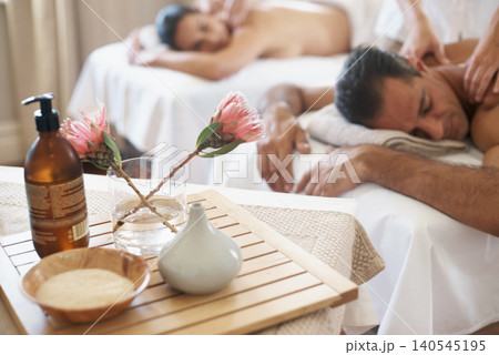 Hotel, flowers and couple in spa to relax on bed or break with luxury pamper treatment tools on table. Protea, facial oil or woman with man at resort or salon for natural healing benefits or massage Hotel, flowers and couple in spa to relax on bed or break with luxury pamper treatment tools on table. Protea, facial oil or woman with man at resort or salon for natural healing benefits or massage 140545195