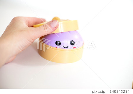 Child's hand playing with happy purple squishy toy 140545254