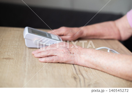 Senior woman measuring blood pressure using medical device Senior woman measuring blood pressure using medical device 140545272