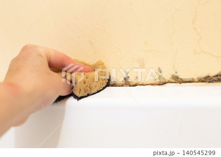 Hand cleaning moldy bathroom wall with sponge Hand cleaning moldy bathroom wall with sponge 140545299