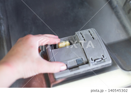 Hand placing detergent tablet in dishwasher dispenser Hand placing detergent tablet in dishwasher dispenser 140545302