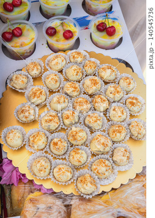 Cheese balls with nuts sit on gold tray beside fruit cups at Kazanluk Rose Festival food event. Cheese snack display shows catering. Dessert selection shows sweets, bakery products 140545736