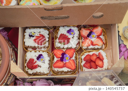 Strawberry cakes with cream, edible flowers sit in boxes, Kazanluk Rose Festival food event. Cake display with bakery craft, dessert market, berries, sweets, Bulgarian cuisine Strawberry cakes with cream, edible flowers sit in boxes, Kazanluk Rose Festival food event. Cake display with bakery craft, dessert market, berries, sweets, Bulgarian cuisine 140545737