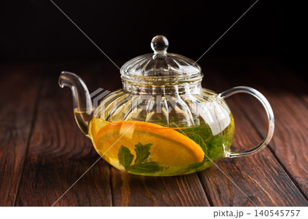 Glass teapot brewing herbal tea with orange and mint Glass teapot brewing herbal tea with orange and mint 140545757