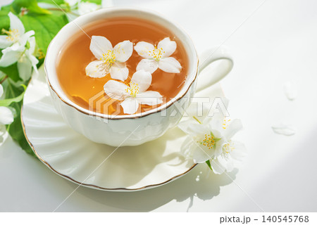 Jasmine floral tea with floating white blossoms in a cup Jasmine floral tea with floating white blossoms in a cup 140545768