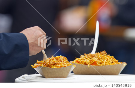 Eating Asian street food noodles from disposable paper trays at Karlin square in Prague Eating Asian street food noodles from disposable paper trays at Karlin square in Prague 140545919