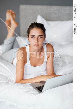 Woman, lying and laptop on bed in portrait for connection, typing and chatting online to relax. Female person, technology and computer for conversation in casual outfit and comfortable in bedroom Woman, lying and laptop on bed in portrait for connection, typing and chatting online to relax. Female person, technology and computer for conversation in casual outfit and comfortable in bedroom 140546245