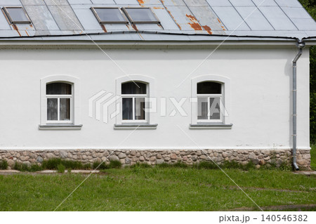 A simple white country house facade featuring three arched windows 140546382