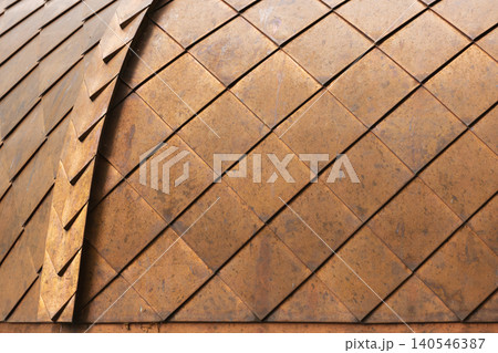 Close-up of copper metal tiles forming a repeating geometric pattern on a domed roof 140546387