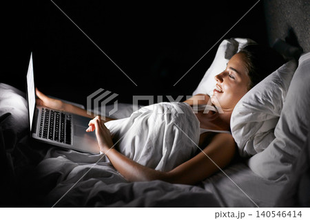 Bedroom, laptop and night with woman streaming content, video or browsing social media in dark home. Bed, computer and subscription with young person in apartment to relax on weekend time off 140546414
