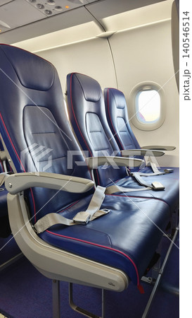Vertical view of interior view of a passenger airplane cabin showcasing blue seats arranged in rows. Highlights air travel comfort, modern design, and in-flight experience. Vertical view of interior view of a passenger airplane cabin showcasing blue seats arranged in rows. Highlights air travel comfort, modern design, and in-flight experience. 140546514