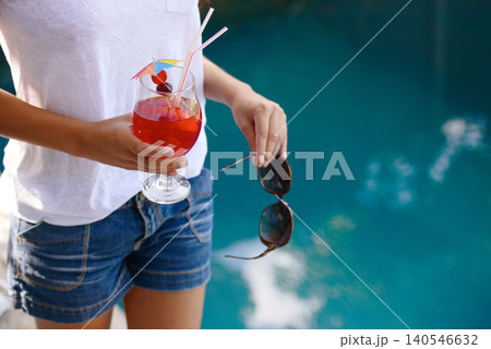 Person, hands and cocktail at pool in summer on holiday or vacation with luxury hospitality at hotel. Alcohol, drink and guest relax outdoor at villa with fashion, style and sunglasses by water Person, hands and cocktail at pool in summer on holiday or vacation with luxury hospitality at hotel. Alcohol, drink and guest relax outdoor at villa with fashion, style and sunglasses by water 140546632