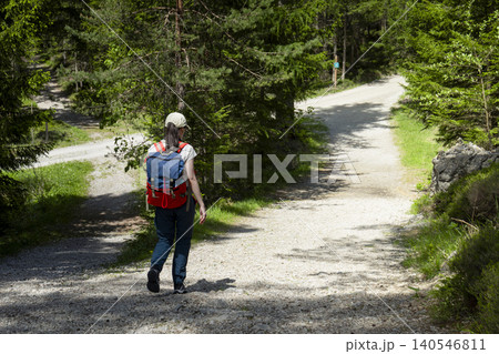 Woman hiker with a backpack at a crossroads in a forest, highlighting connection with nature through physical activity Woman hiker with a backpack at a crossroads in a forest, highlighting connection with nature through physical activity 140546811
