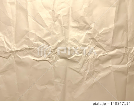 crinkled cream paper texture capturing organic folds, raw creases, and tactile highlights in a full frame background 140547114