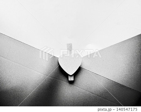 minimalist black and white art photo featuring heart wooden clip joining paper envelope with textured lines and white background minimalist black and white art photo featuring heart wooden clip joining paper envelope with textured lines and white background 140547175