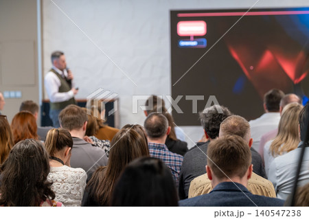 Business conference presentation with attentive audience listening to speaker on stage Business conference presentation with attentive audience listening to speaker on stage 140547238