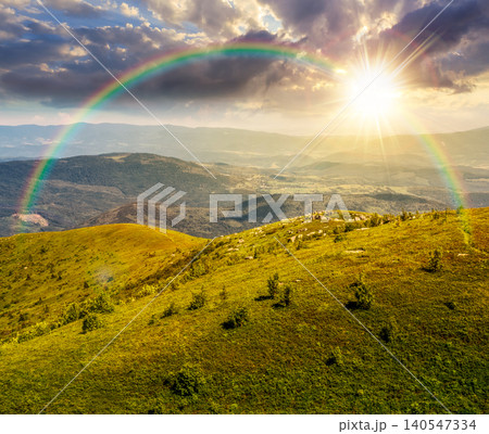 sunset over mountain landscape with alpine meadow in dappled light. carpathian mountain scenery in summer. view in to the distant valley landscape. rolling hills and grassy meadow under the rainbow sunset over mountain landscape with alpine meadow in dappled light. carpathian mountain scenery in summer. view in to the distant valley landscape. rolling hills and grassy meadow under the rainbow 140547334