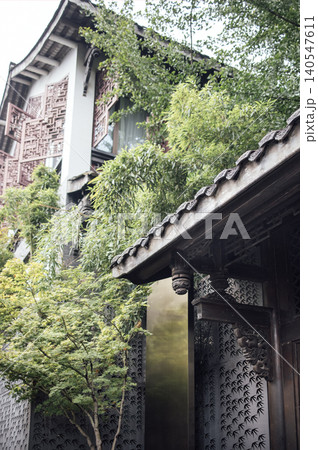 Traditional Asian architecture featuring intricate wooden details and lush greenery surrounding a serene entrance in a tranquil garden setting Traditional Asian architecture featuring intricate wooden details and lush greenery surrounding a serene entrance in a tranquil garden setting 140547611