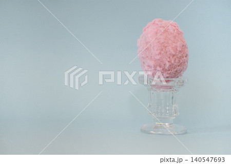 Pink cotton candy displayed in a clear glass dessert cup against a soft blue background, highlighting the fluffy texture and vibrant color of the treat Pink cotton candy displayed in a clear glass dessert cup against a soft blue background, highlighting the fluffy texture and vibrant color of the treat 140547693