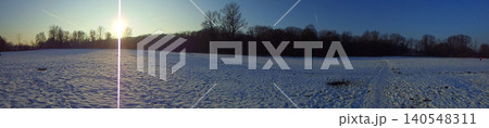 Light damaged wide angle image of snow-covered meadow under setting sun. 140548311