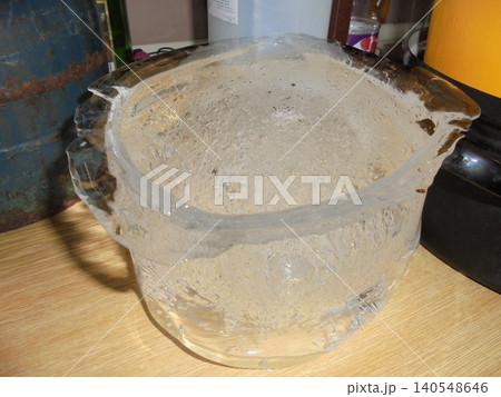 Bucket-shaped piece of ice with bubbles of air inside standing on a ktichen unit Bucket-shaped piece of ice with bubbles of air inside standing on a ktichen unit 140548646