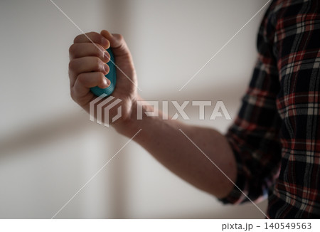 Man's Hand Firmly Gripping A Rubber Trainer 140549563