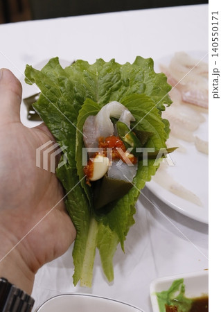 Hand Holding Fresh Lettuce Wrap with Seafood and Garnishes 140550171