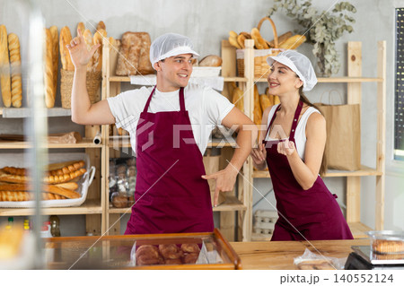 Pair of young bakers in aprons joyfully dancing in bakery 140552124