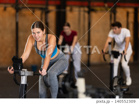 Focused girl works out with exercise bicycle during class at fitness club 140552309