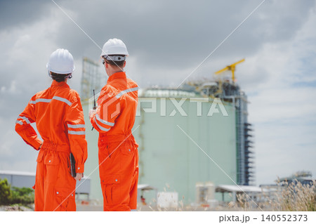 Oil and gas engineers surveying LNG tank site with digital tablet and communication tools Oil and gas engineers surveying LNG tank site with digital tablet and communication tools 140552373