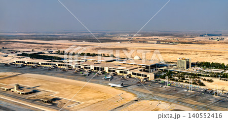 High angle view of the King Fahd International Airport terminal and tarmac in Dammam, Saudi Arabia, featuring airplanes parked at gates and the surrounding desert landscape. 140552416