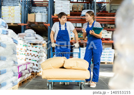 Girl check papers invoices together with guy employee and revise availability of goods in stock Girl check papers invoices together with guy employee and revise availability of goods in stock 140553155