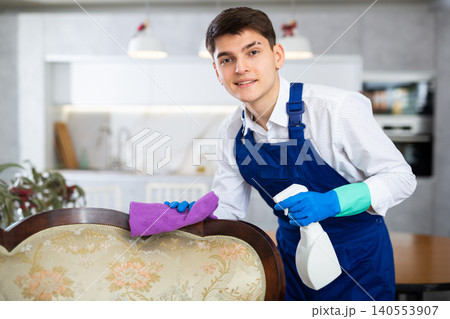 Professional cleaner cleans and dusts the furniture in room Professional cleaner cleans and dusts the furniture in room 140553907