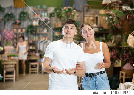 Married couple look for something in room garden furniture store, searching for item to complete patio. Woman with husband buyers looks around in showroom Married couple look for something in room garden furniture store, searching for item to complete patio. Woman with husband buyers looks around in showroom 140553920