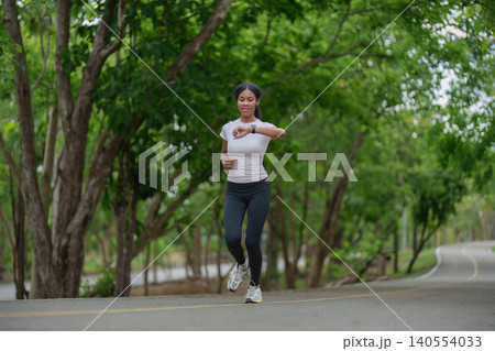 Black woman running outdoors checking smartwatch for fitness tracking and healthy lifestyle park Black woman running outdoors checking smartwatch for fitness tracking and healthy lifestyle park 140554033