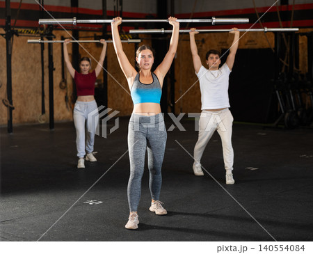 Slender girl trains muscles of arms and back using barbell and differentiated weighting in gym Slender girl trains muscles of arms and back using barbell and differentiated weighting in gym 140554084