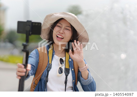 Happy Asian woman vlogging outdoors with smartphone for travel content creation and social media Happy Asian woman vlogging outdoors with smartphone for travel content creation and social media 140554097