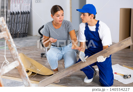 Young woman talking to builder during laminate flooring installation in apartment 140554227