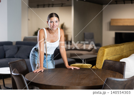 Woman visiting furnishing store in search of comfortable dining table for home 140554303