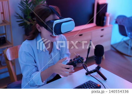 Asian woman playing VR gaming virtual reality headset with controller for technology entertainment Asian woman playing VR gaming virtual reality headset with controller for technology entertainment 140554336