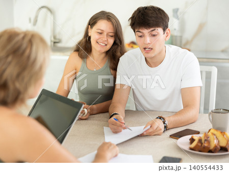 Married couple of clients listen attentively and intently to woman of seller, who tells about advantages of making microloan in credit institution in home 140554433