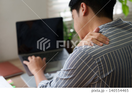 Man with shoulder pain working on laptop for remote work health Man with shoulder pain working on laptop for remote work health 140554465