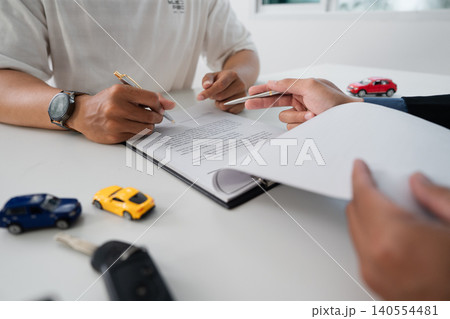 Two men signing car purchase agreement document at office desk 140554481