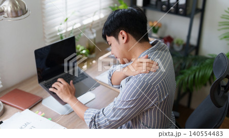 Asian man experiencing shoulder pain while working on laptop 140554483